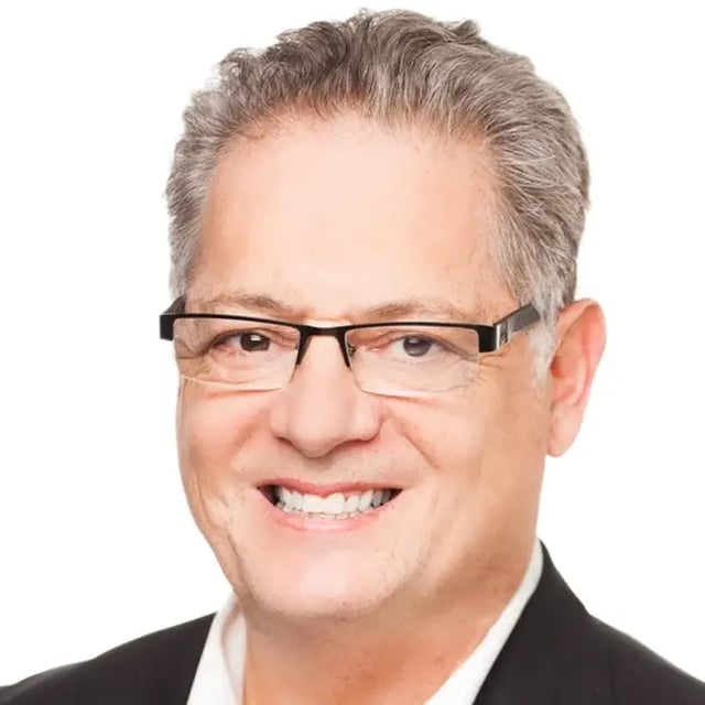 Portret van Rob Brimm met een glimlach, bril en grijs haar tegen een witte achtergrond.