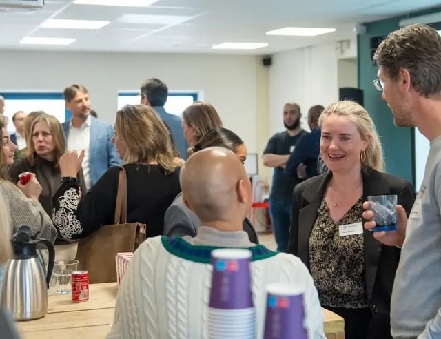 Groep mensen in gesprek tijdens een informele klantendag borrel in een kantoorruimte.
