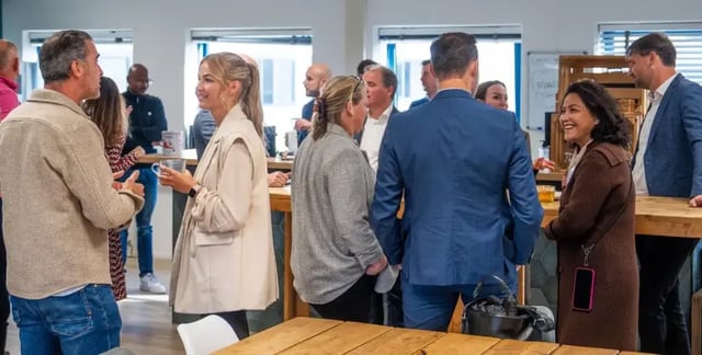 Groep mensen in gesprek tijdens een klantendag op een informele netwerklocatie.